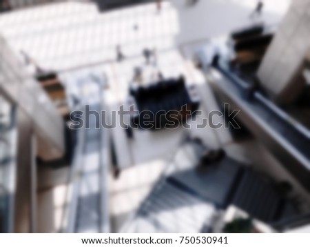 Top view of people walking and escalator in shopping mall. Intentional blurred added post production. Creative abstract background with blurred in modern style.