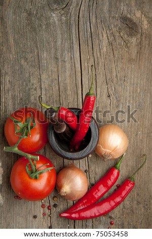 Top view on tomato, onions and red hot chili peppers in old mortar on old wooden table Royalty-Free Stock Photo #75053458