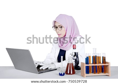 Young female researcher working on a laptop computer with test tube and microscope on the table