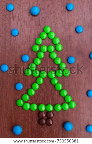 Christmas green pine tree made of colorful sweet chocolate round candies New year 2018 on a rustic wooden background . Holiday concept. Snow imitation
