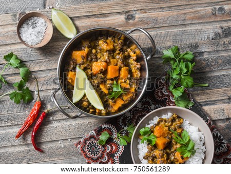 Pumpkin lentil curry and rice on a wooden table, top view. Indian vegetarian food concept Royalty-Free Stock Photo #750561289