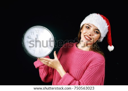 Young woman in Santa hat holding clock .Christmas time