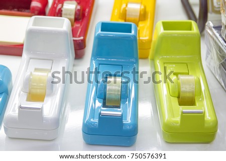 3 multi-colored tape dispensers placed on a white desk