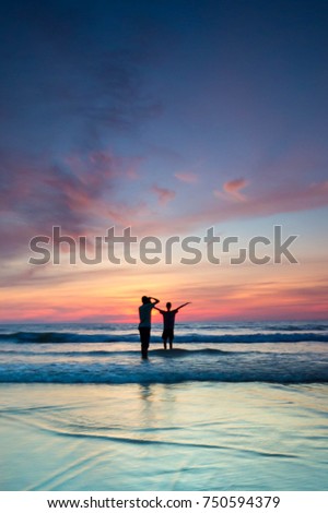 silhouette of people on a beach. The image may contain blurry effect due to low light condition and long exposure