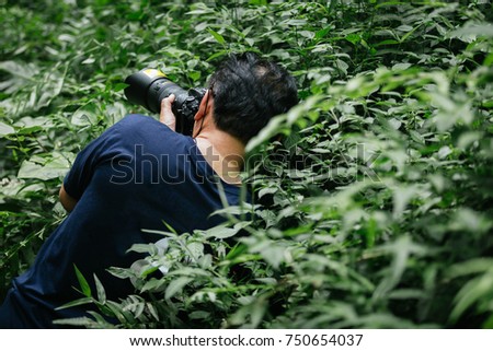 Photographers are photographed in the wilderness by the grass.