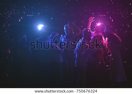 Happy friends at birthday party at night club. Classy people enjoying life, dancing, drinking champagne and having fun at dark smoky background, showered with confetti. B-day celebration background