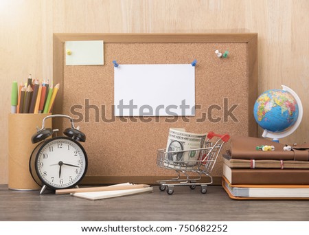 blank paper note on cork board with alarm clock, book on wooden desk.