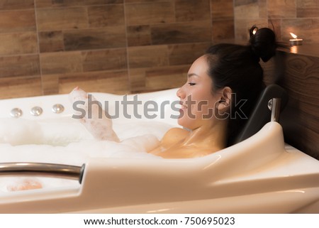 Bathing woman relaxing in bath smiling relaxing. Multicultural Asian / Caucasian young woman in bathtub.