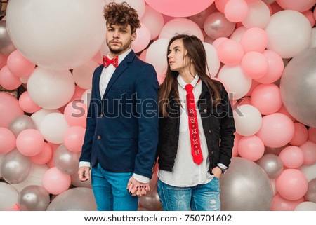 Stylishly dressed couple with red tie and bow tie walking along the street