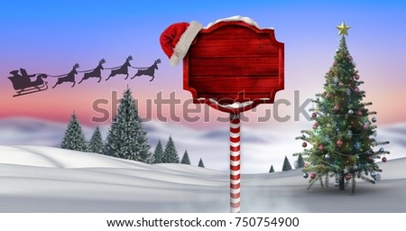 Digital composite of Wooden signpost in Christmas Winter landscape with Christmas tree and Santa's sleigh and reindeer's