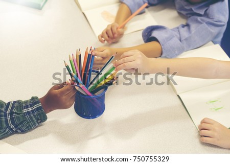Hands of little child pick a colored pencils on the table, 
Little child drawing with colored pencils. Creative style.

