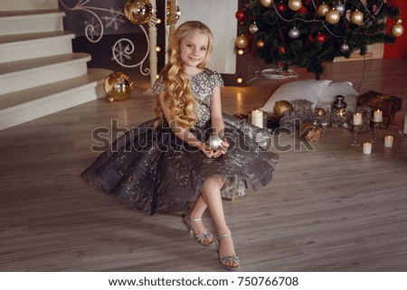 pretty little girl near the new year tree. beautiful girl in dress near Christmas tree waiting for holiday. Interior with christmas decorations.