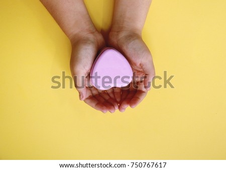 Woman hands hold metal heart in yellow background .She show sent and receive is love.
