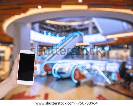 Hand holding mobile phone with Shopping mall or department store blurred background and bokeh light, Social network, internet