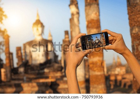 A hand taking photo of Buddha statue with smartphone, Sukhothai, Thailand