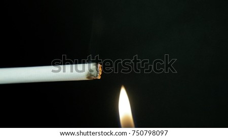 Burning cigarette with smoke on black background. Man ignites a cigarette. Smoking slow motion
