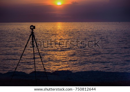 professional camera stand on tripod photographing sea, twilight sky and cloud landscape. 