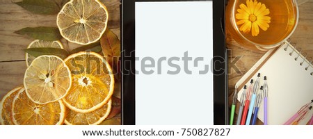 tablet lying on the table next to tea and oranges 