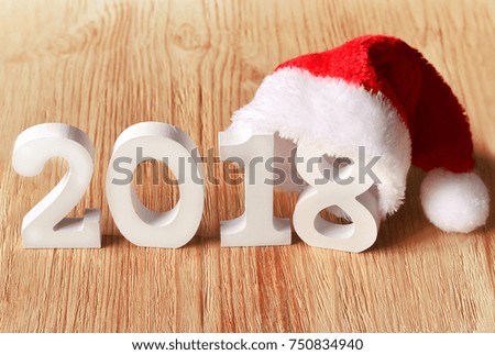 santa fur cap on a rustic wooden background with figures 2018