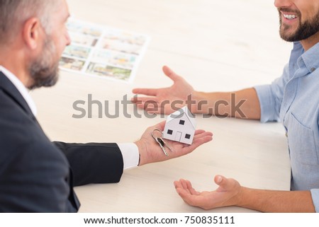 Real estate agent giving a new owner apartment keys with house shaped keychain