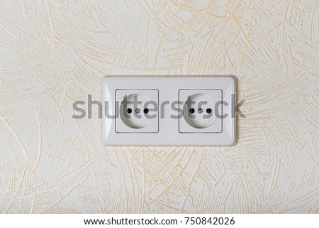 Light wallpaper on a wall with electrical outlet for background. Close Up detail.