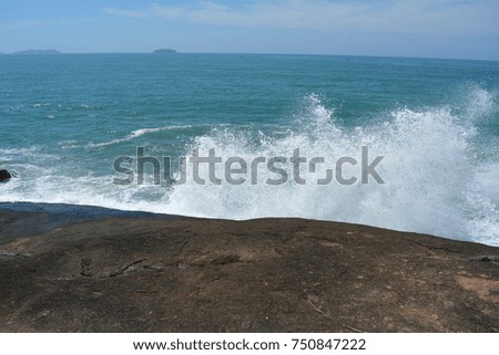 Wave hitting rock on sunny day