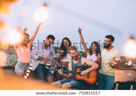 Group of happy friends having party on rooftop Royalty-Free Stock Photo #750851017