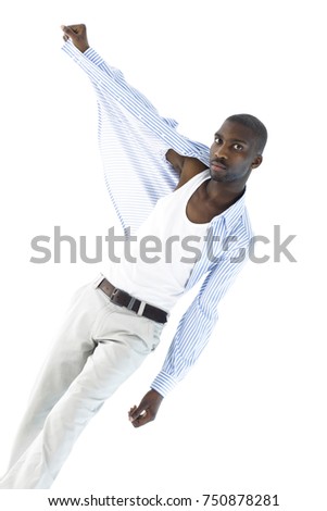 African man with a blank expression is taking off his shirt while walking towards camera