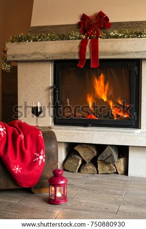 Fireplace decorated for Christmas. Glass of red wine and appetizer on wooden table, fireplace for background.