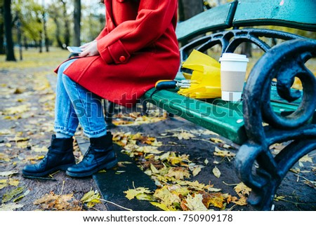 woman on the bench in park with umbrella and cup of coffee in autumn day