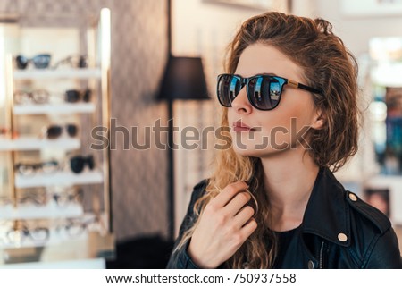 Happy woman buying sunglasses in shop.