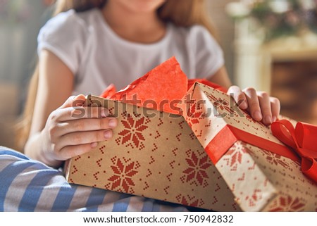 Happy holidays! Cute little child opening gift at Christmas. Close up. 