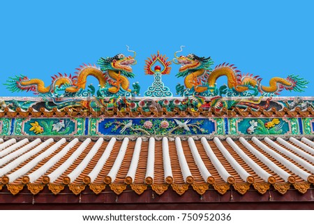 Two chinese dragons statue chasing the flaming pearl on the roof of the temple with blue sky in background