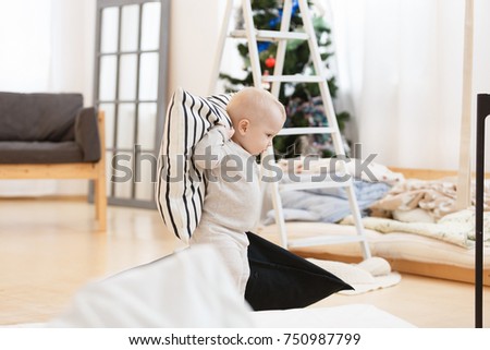 portrait of the small baby in a light cozy living room. New year picture. White clothes, happy childhood, christmastime