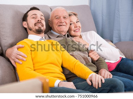 Mature parents and adult son happy to spend time together at home