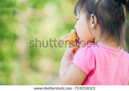 Cute happy baby girl are eating ice cream in summer. Picture for concept of sweet ,fat ,obesity and diabetes in children.Soft focus. 