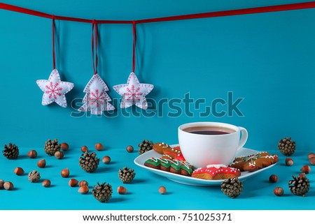 Black tea and gingerbread in a white crockery. Black tea and gingerbread in white crockery among the Christmas decorations on a light blue wooden background.