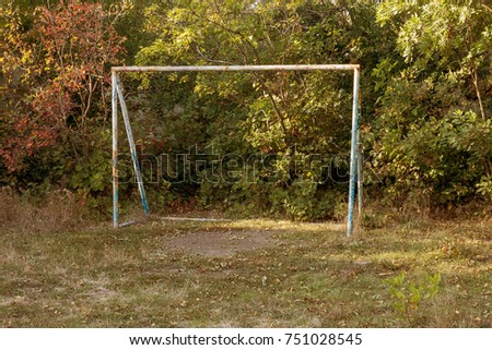 Old iron rusty football goal for mini football on trampled lawn in forest zone of city park. Old small football gate in park. Hand football gate in middle of meadow in countryside