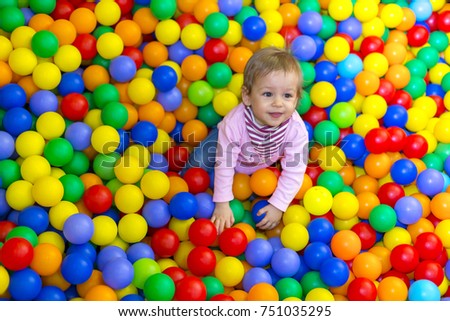 Child playing with colorful balls in playground ball pool. Activity toys for little kid.