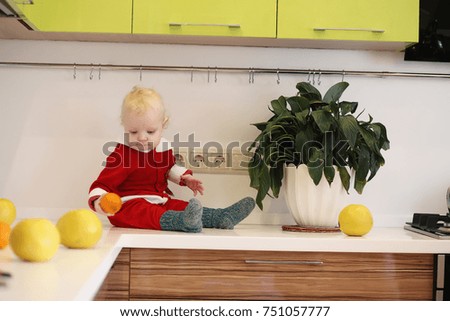 Little blond child in the kitchen sits on a table
