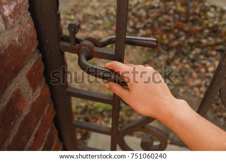 The hand opens old metal wrought iron door. The way of the future