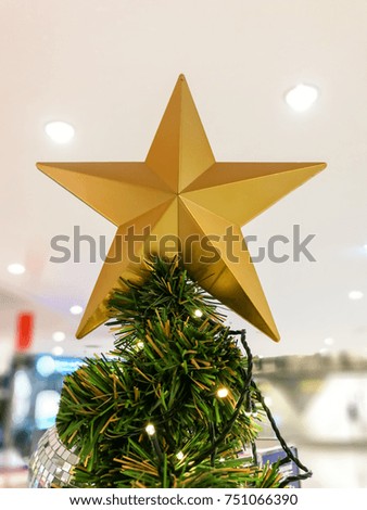 Christmas tree is decorated with the golden star on top, glass ball and glittery golden ball. White blur background.