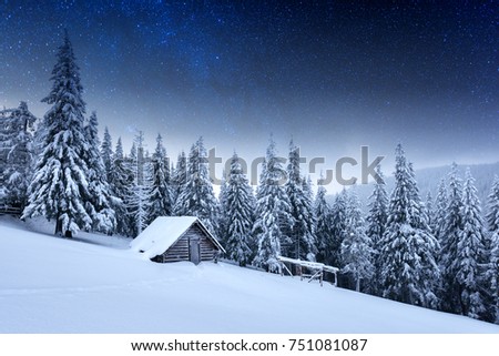 Fantastic winter night landscape glowing by stars light. Dramatic wintry scene with wooden snowy house. Carpathian mountains, Ukraine, Europe. Christmas holiday background