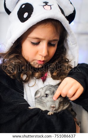 a little girl dressed in a bear costume Panda. holds rodent chinchilla