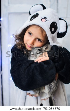 a little girl dressed in a bear costume Panda. holds rodent chinchilla