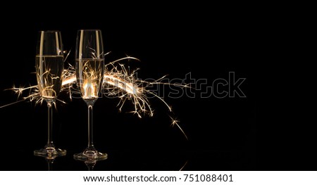 Two tall glasses of champagne in Bengal lights. Black background. Silhouette. The concept of celebration. New Year celebration.