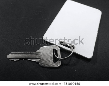 key with a label and key card placed on a black sofa.