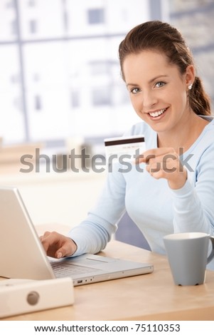 Young woman using laptop, shopping on internet, using credit card, smiling.?