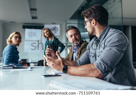Businessman putting forward his suggestions to colleagues. Startup business team on meeting in modern bright office. Royalty-Free Stock Photo #751109761