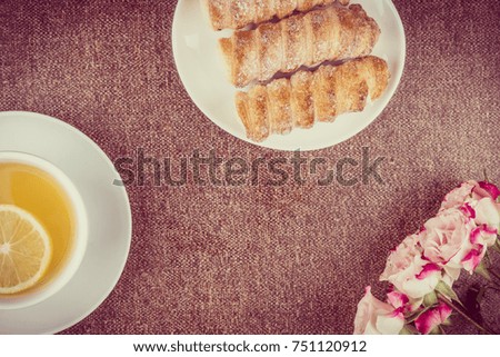 Tea with a slice of lemon, cakes and roses